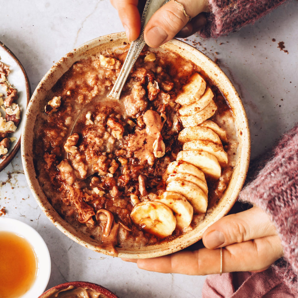 Holding a spoon in a bowl of banana bread steel cut oats