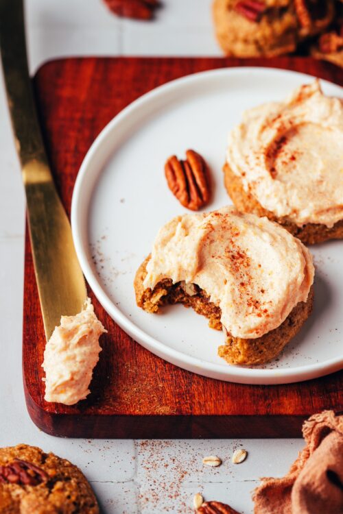 Plate with two pumpkin cookies topped with frosting for our round-up of cozy fall desserts