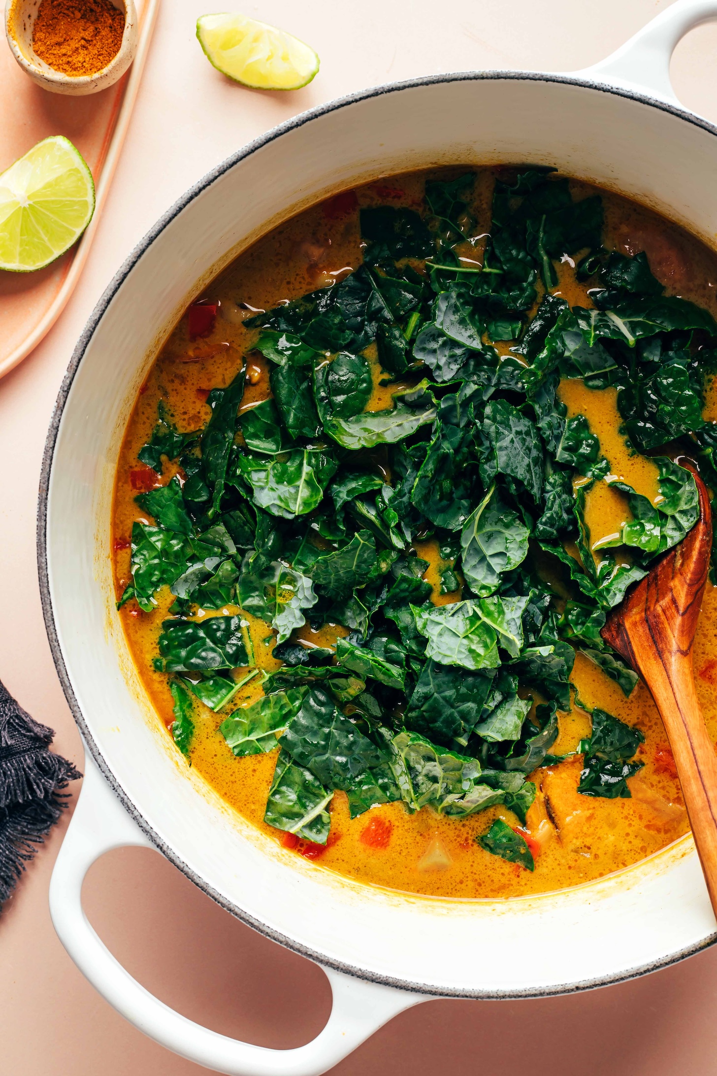 Dutch oven of vegan black eyed pea soup topped with chopped kale