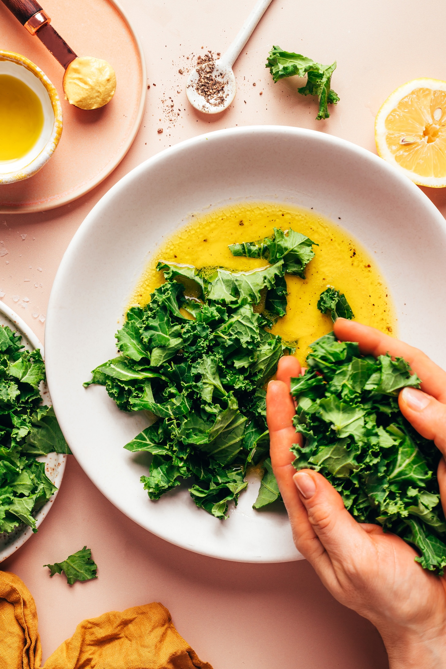 Adding chopped kale to a bowl of homemade lemon maple vinaigrette
