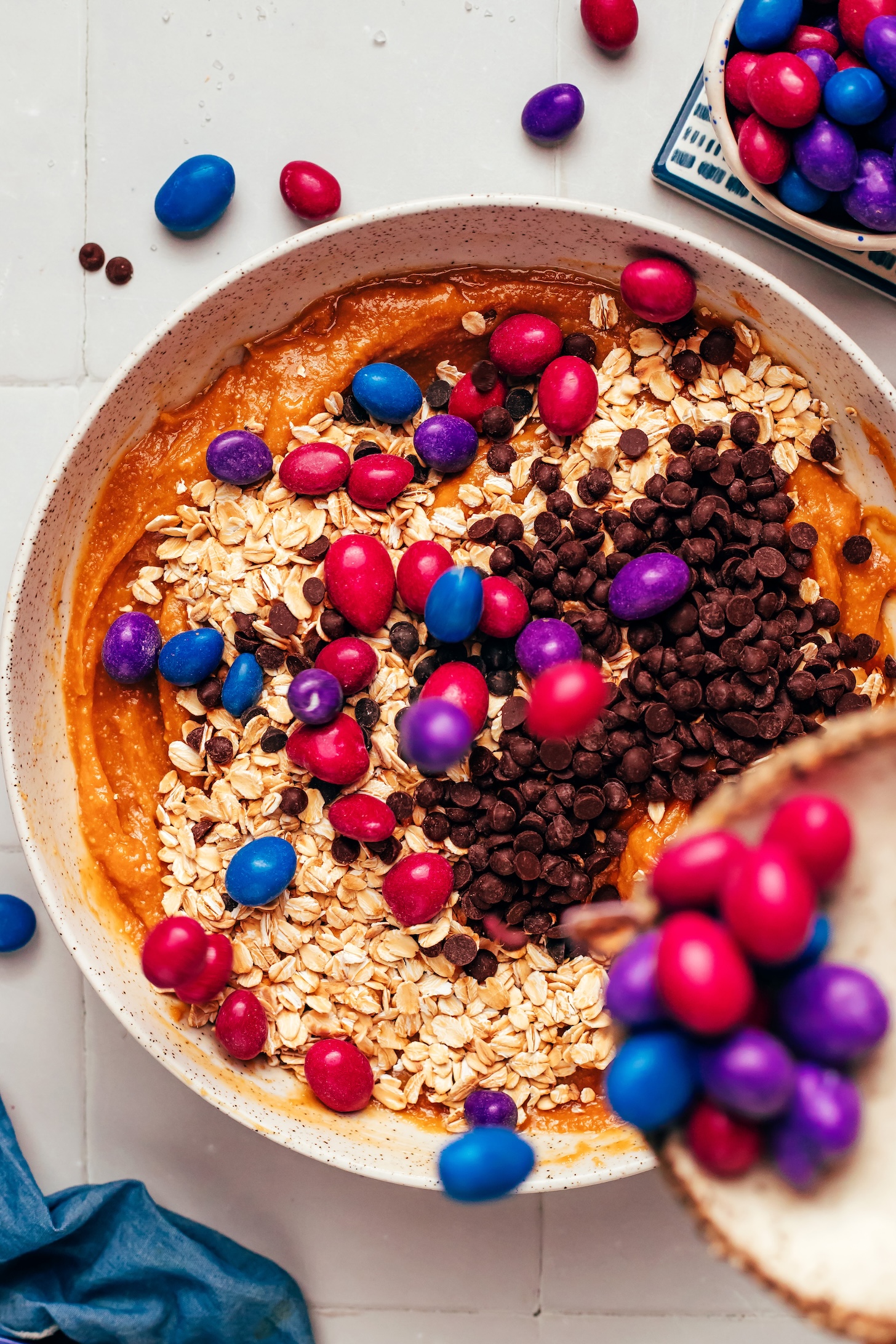 Pouring natural chocolate peanut candies into a bowl of cookie dough