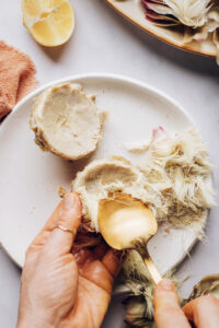 Using a spoon to remove the choke from an artichoke heart