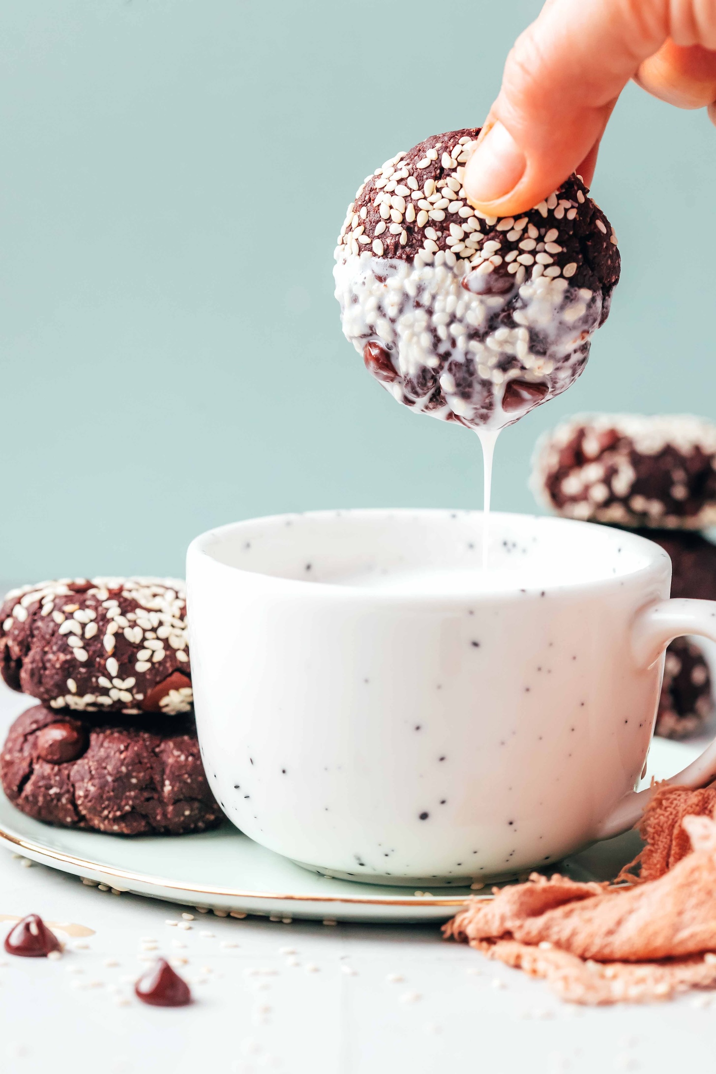 Chocolate tahini cookie freshly dunked into a mug of dairy-free milk