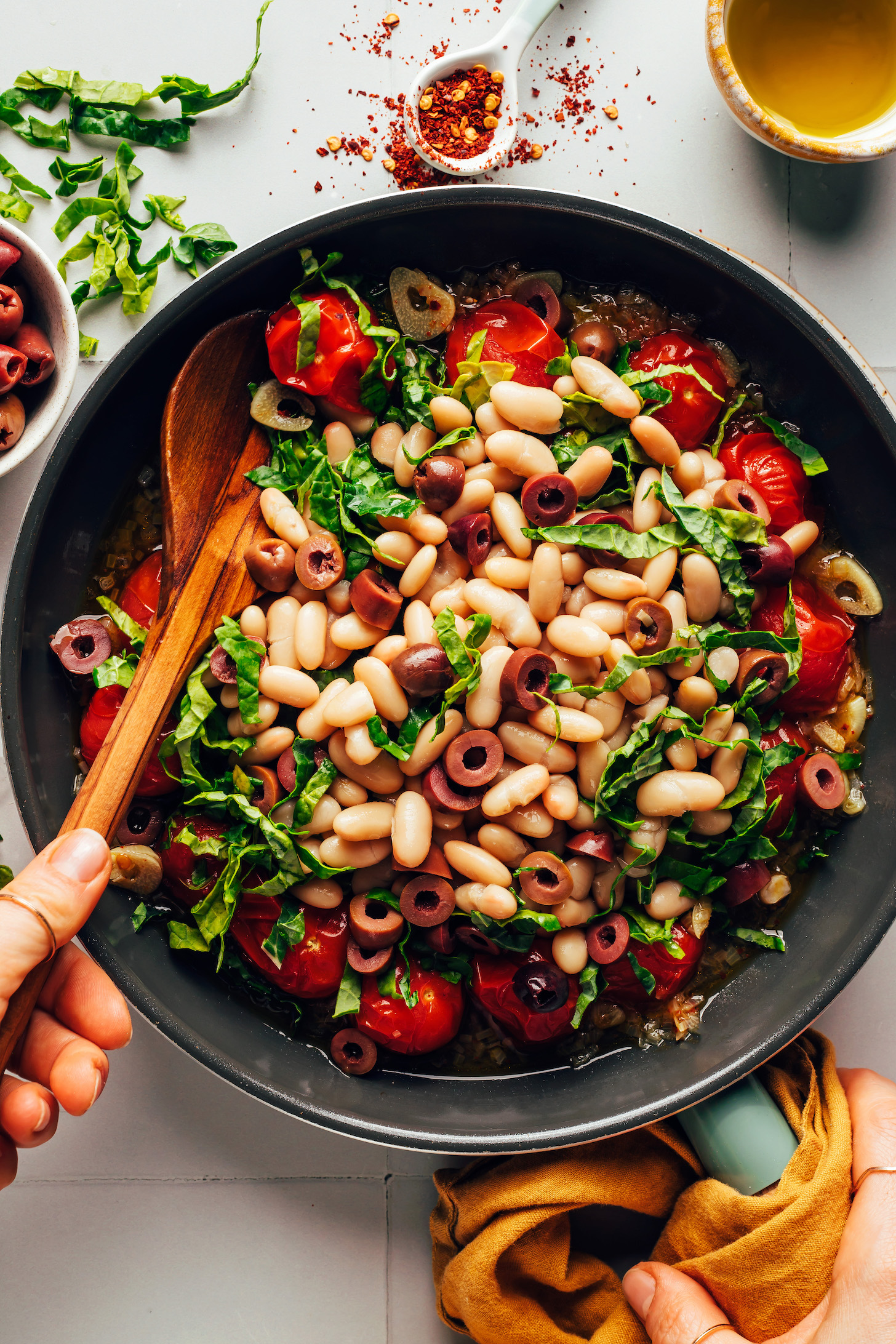 Sauté pan with sautéed veggies, white beans, and olives