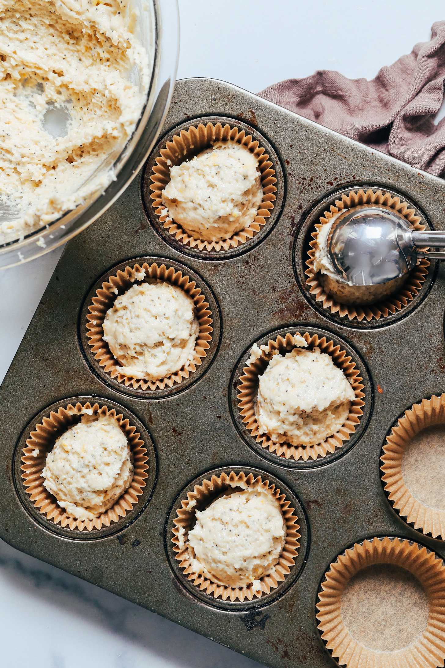 Using an ice cream scoop to scoop muffin batter into a muffin tin