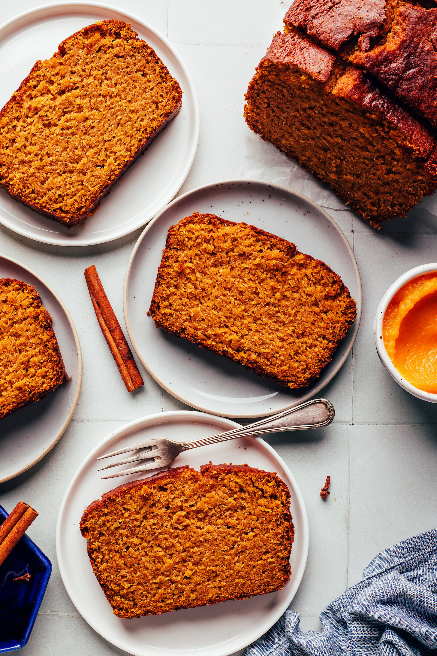 Slices of our best gluten-free pumpkin bread on a plate next to the rest of the loaf