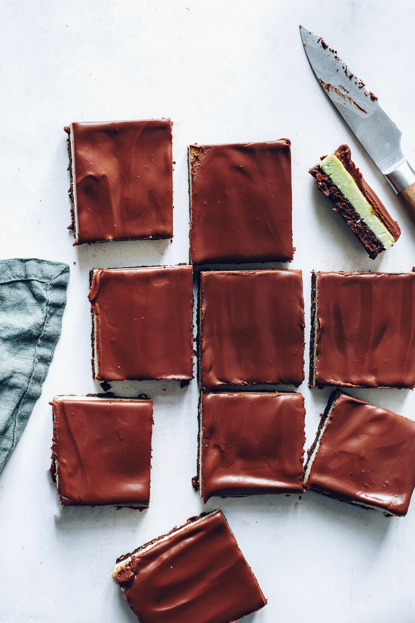 Squares of chocolate mint brownie bars with brownie, mint, and ganache layers