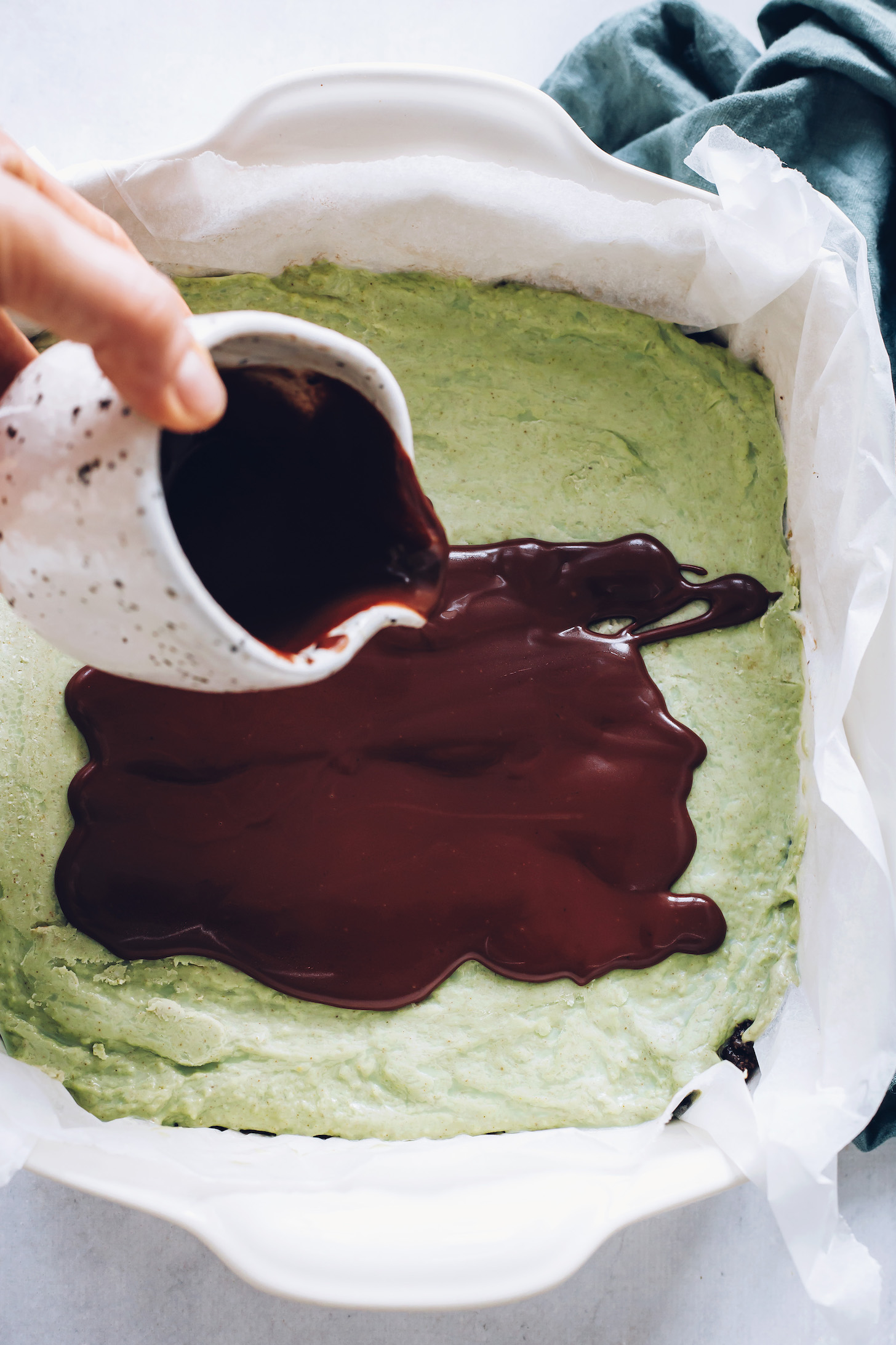 Pouring melted chocolate ganache over the mint layer