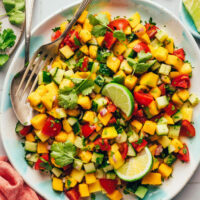 Overhead photo of a bowl of our Easy Mango Cucumber Salad topped with two lime wedges