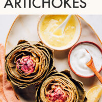 Plate of freshly cooked artichokes with vegan dipping sauces on the side