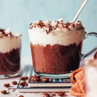 Mug of mocha chia pudding topped with coconut whipped cream and shaved dark chocolate