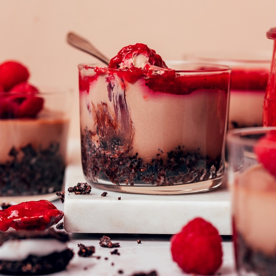 Spoonful of our no-bake chocolate cheesecake and raspberry compote in a glass dessert jar