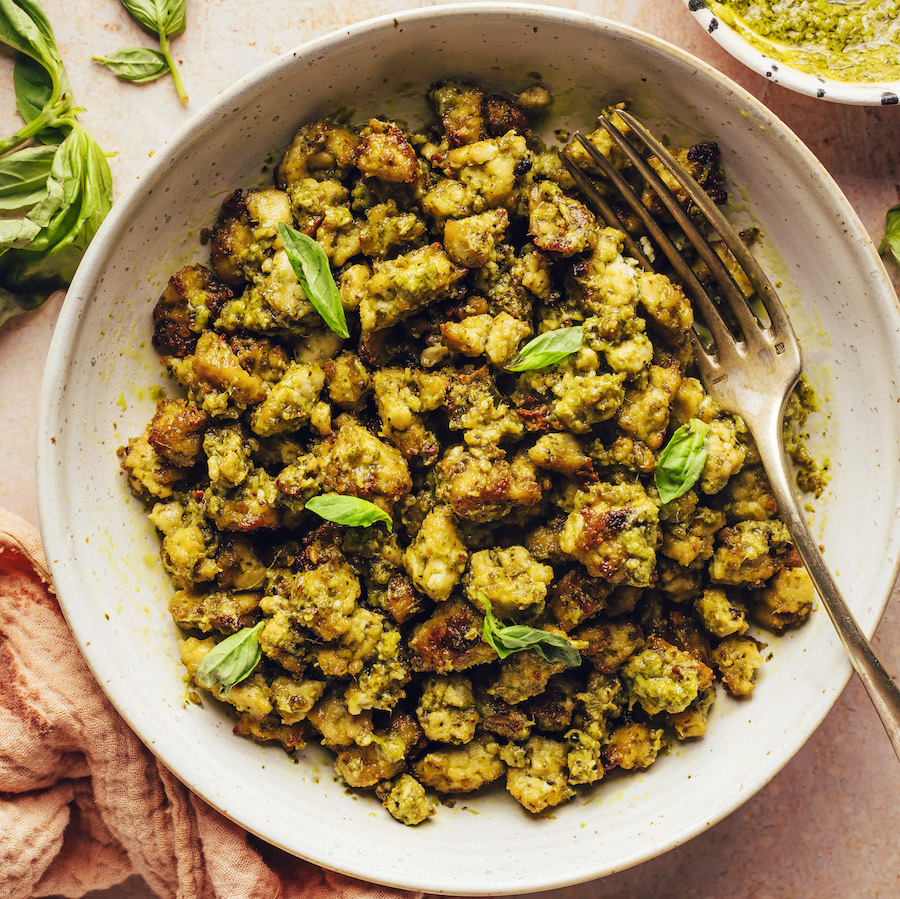 Bowl of crispy pesto baked tofu topped with fresh basil leaves
