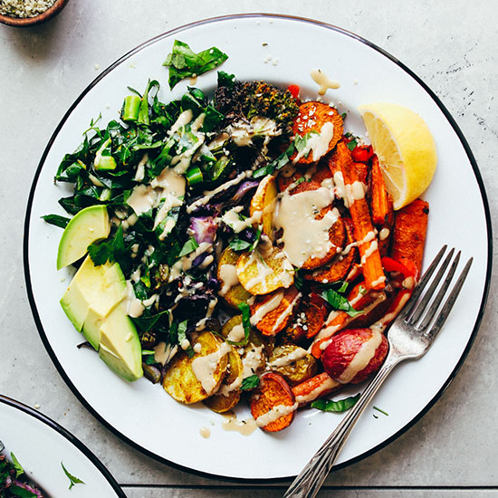 Big bowl of roasted vegetables and avocado topped with tahini dressing