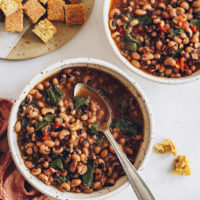 Two bowls of Instant Pot Black Eyed Peas and Greens with vegan cornbread