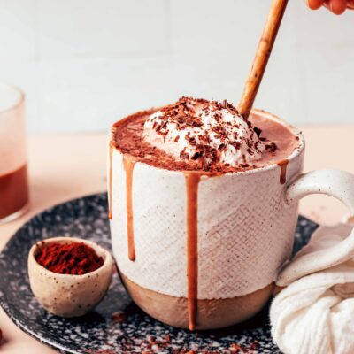Using a small wooden spoon to stir a mug of tahini hot chocolate