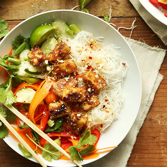 Chopsticks resting on a bowl filled with our Thai Noodle Bowl recipe with Crispy Almond Butter Tofu