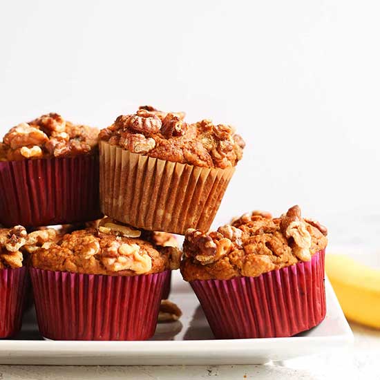 Tray of Gluten-Free Vegan Banana Muffins with a fresh banana in the background