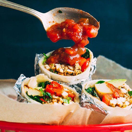 Using a spoon to put salsa onto a Vegan Breakfast Burrito