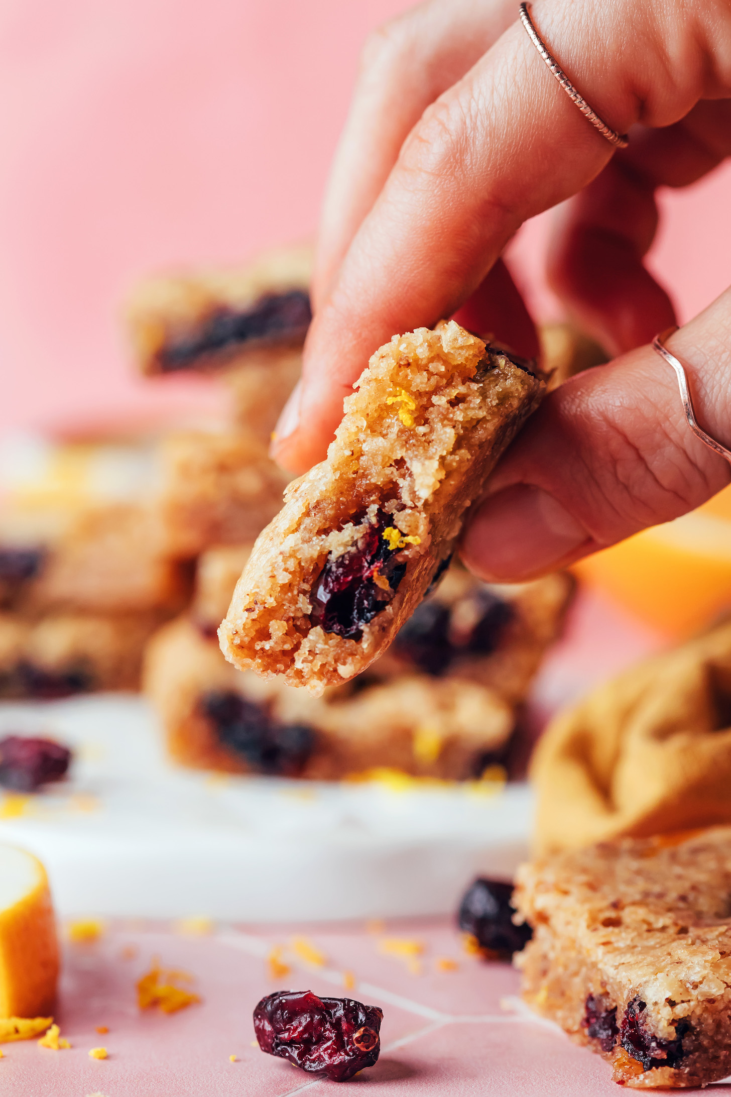 Close up photo of fingers holding a cranberry orange cookie bar