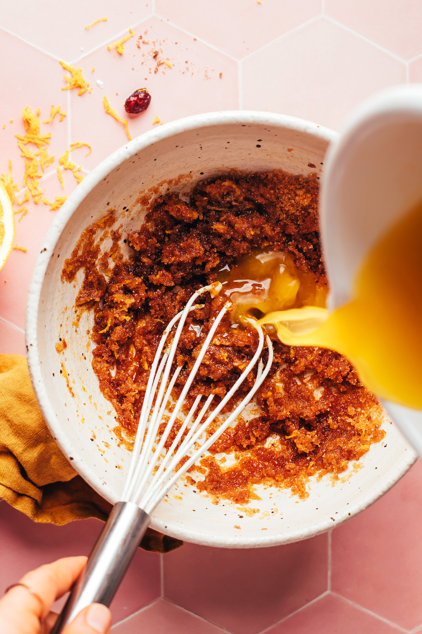 Pouring orange juice into a bowl of wet ingredients